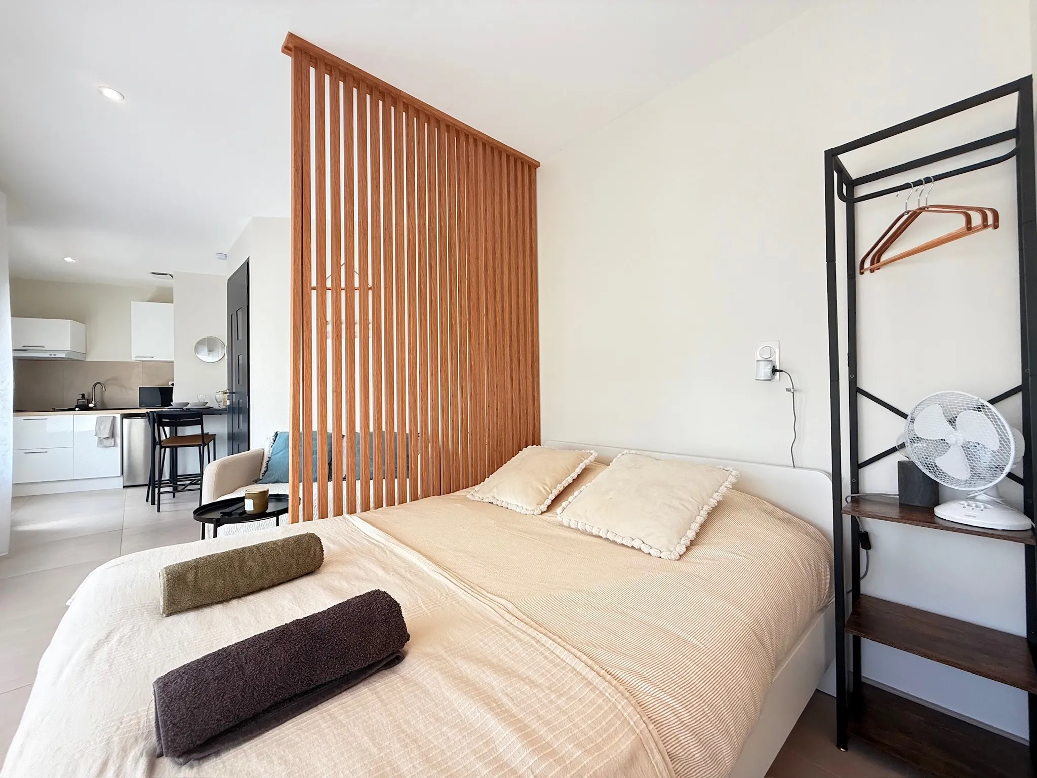 Studio avec lit double et claustra en bois qui sépare le coin nuit de la pièce de vie