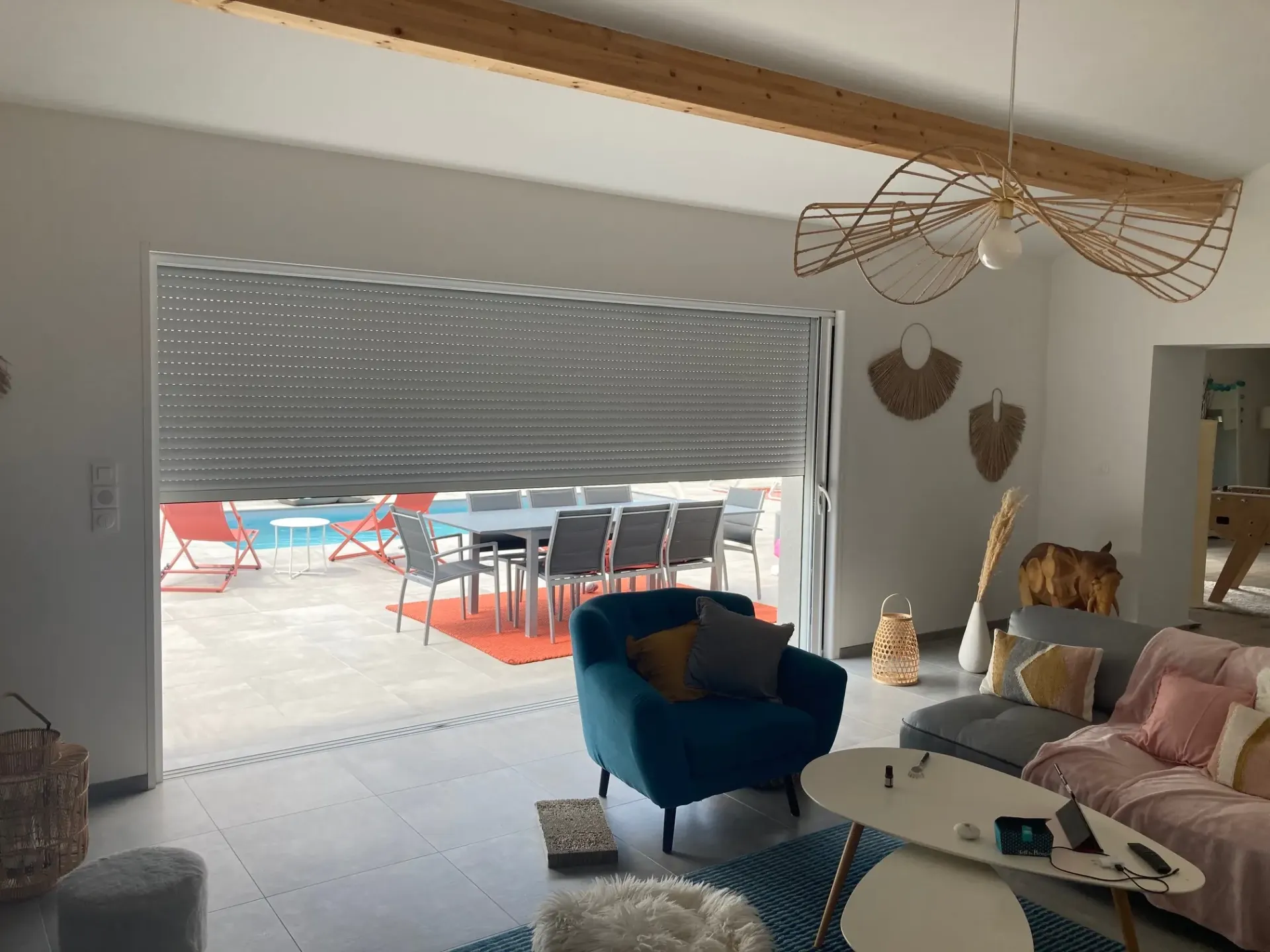 Grande baie coulissante avec volet roulant baissé, donnant sur la terrasse et la piscine