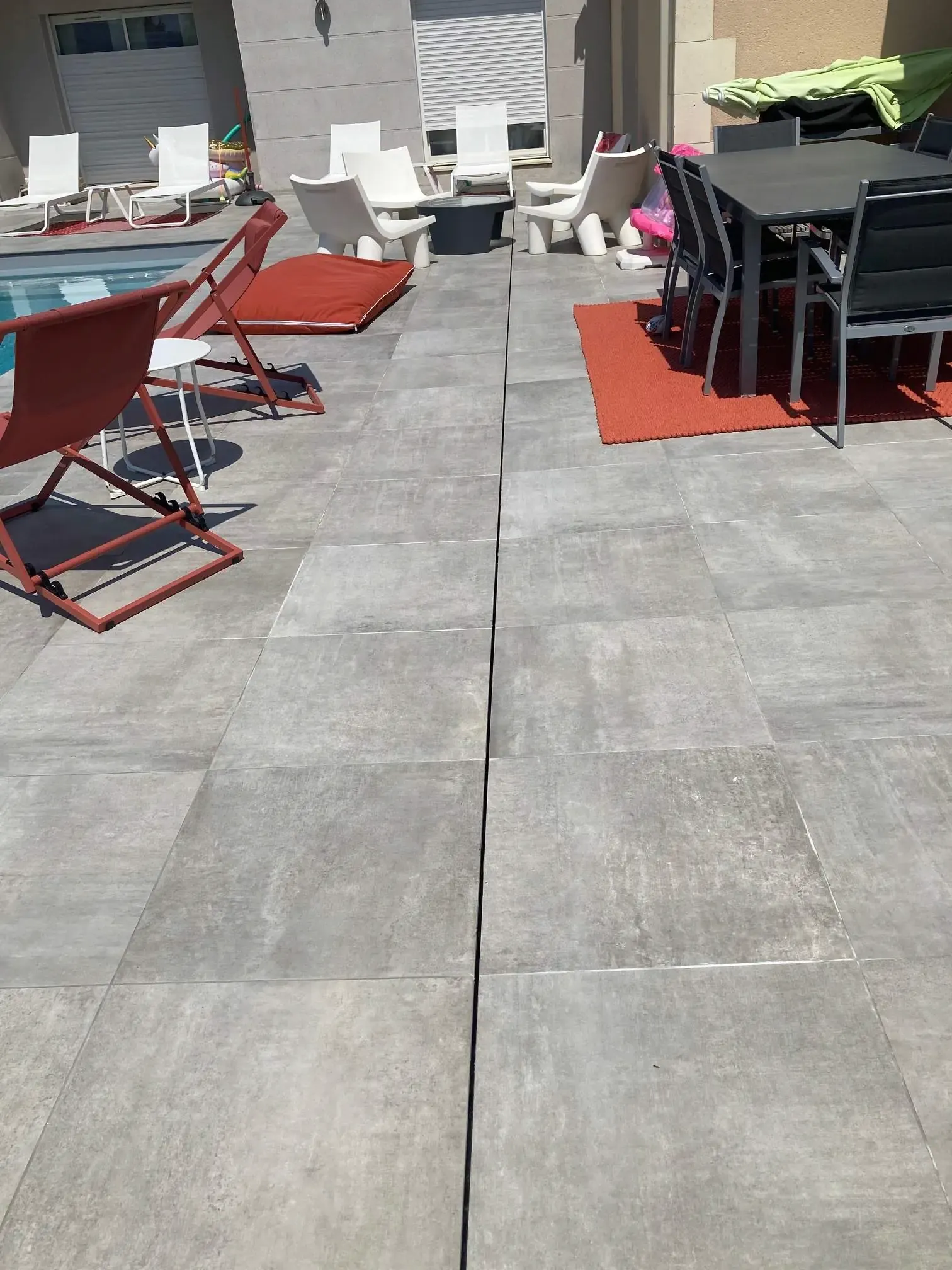 Dalles gris clair posées avec un joint fin, près de la piscine et de la table de jardin